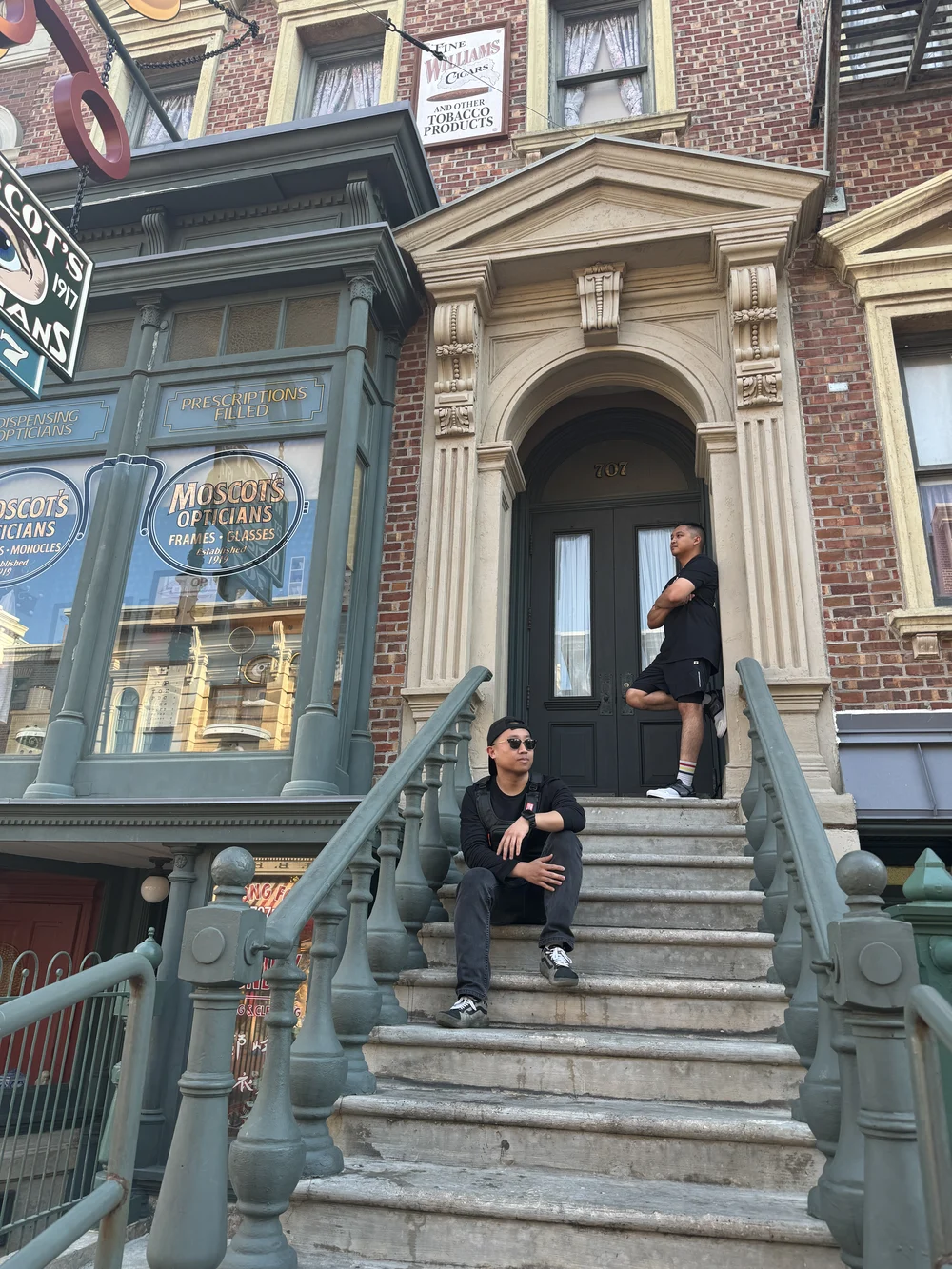 Masa sitting on brownstone steps with his brother standing behind him